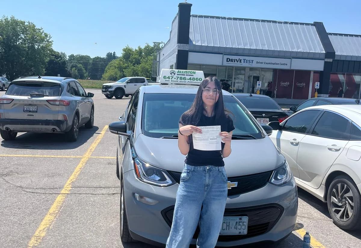 A successful Alliston Driving School student beside the instructor car at a DriveTest centre.